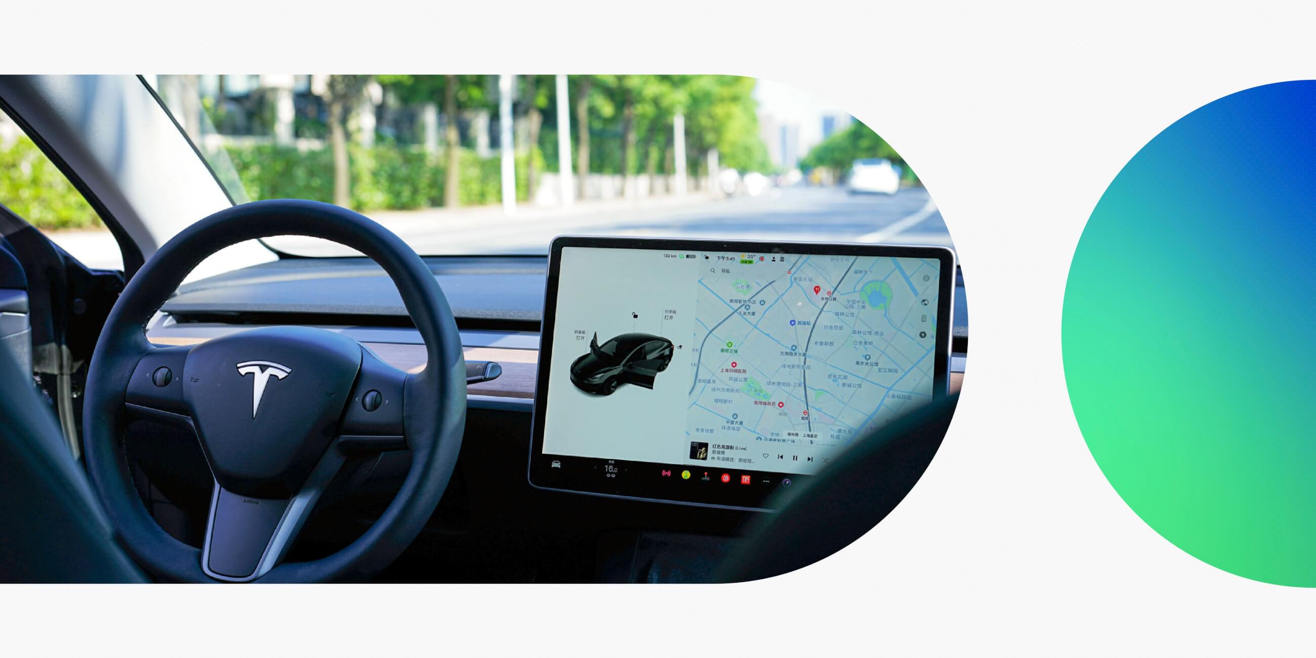 Interior of a Tesla in self-driving mode, showing steering wheel and central touchscreen with active navigation.